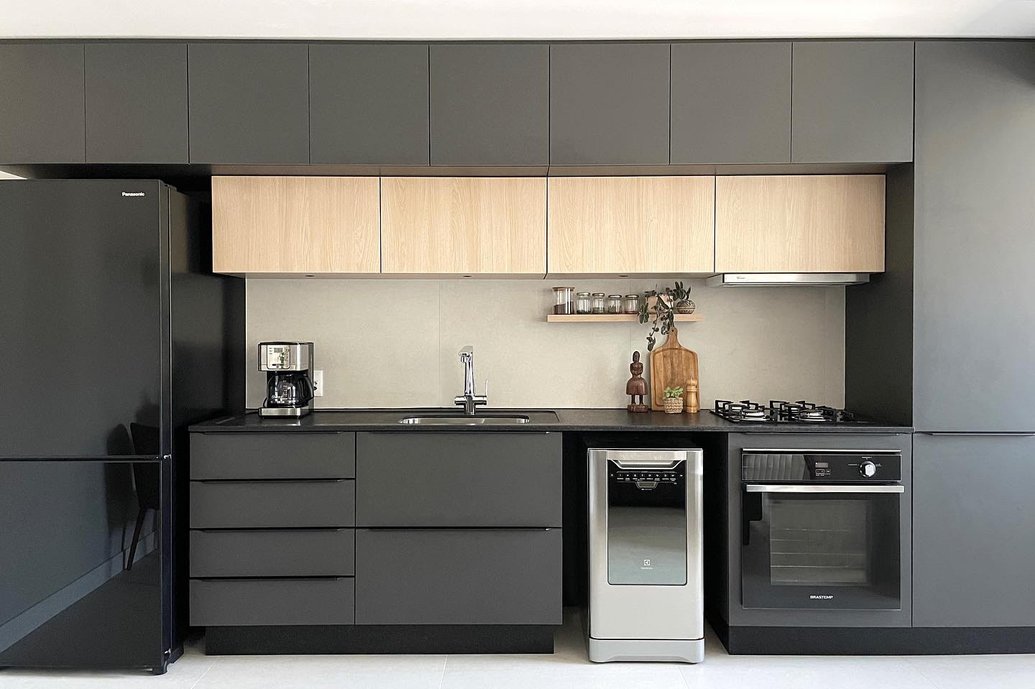 Cozinha com marcenaria, bancada e eletrodomésticos pretos. Backsplash em Porcelanato Via Durini.
