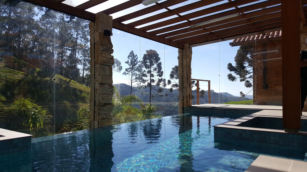Piscina aquecida com borda infinita em sítio, em Rancho Queimado/SC. A borda infinita integra com a paisagem exuberante.