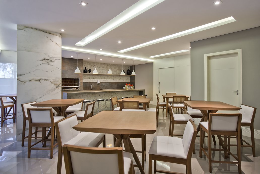 Com o objetivo de marcar o espaço e enriquecer os elementos estruturais, a coluna foi revestida com o porcelanato Bianco Paonazzetto e se tornou um elemento decorativo, assim como a bancada e a parede de fundo no Mos Paonazzetto Classic. A bancada e o volume da churrasqueira revestidas com o porcelanato Steel Corten fazem contraste com os demais revestimentos, quebrando a cor clara do ambiente, mas permanecendo a sofisticação do espaço.