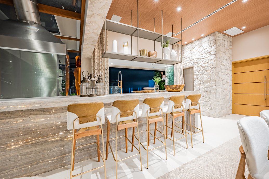 Área gourmet integrada com jantar e living, com pedra retroiluminada na bancada.
Foto: Henrique Ogata