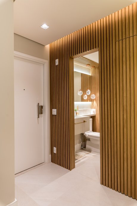 Vista do Hall para o Lavabo, ambos com o mesmo porcelanato Ms. Barcelona Cristal. Quando utilizamos o mesmo porcelanato, temos uma continuidade do revestimento, que adentra de um ambiente ao outro.
