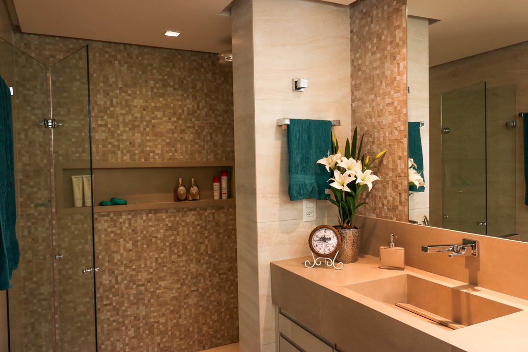 Banheiro suíte com nicho, bancada e cubas esculpidas em porcelanato.