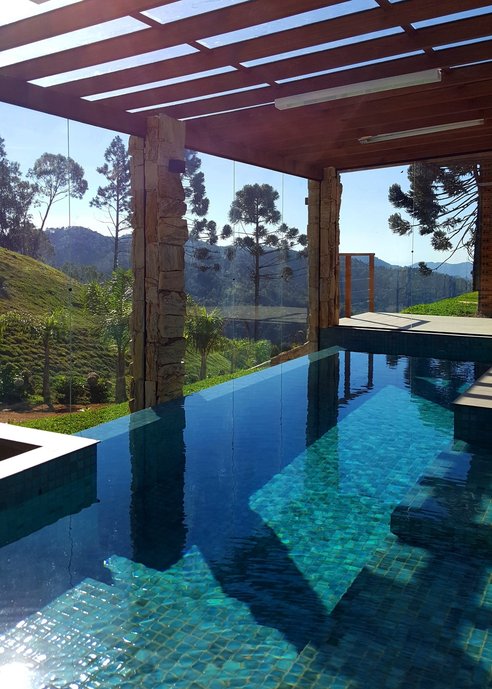 Piscina aquecida com borda infinita em sítio, em Rancho Queimado/SC. A borda infinita integra com a paisagem exuberante.