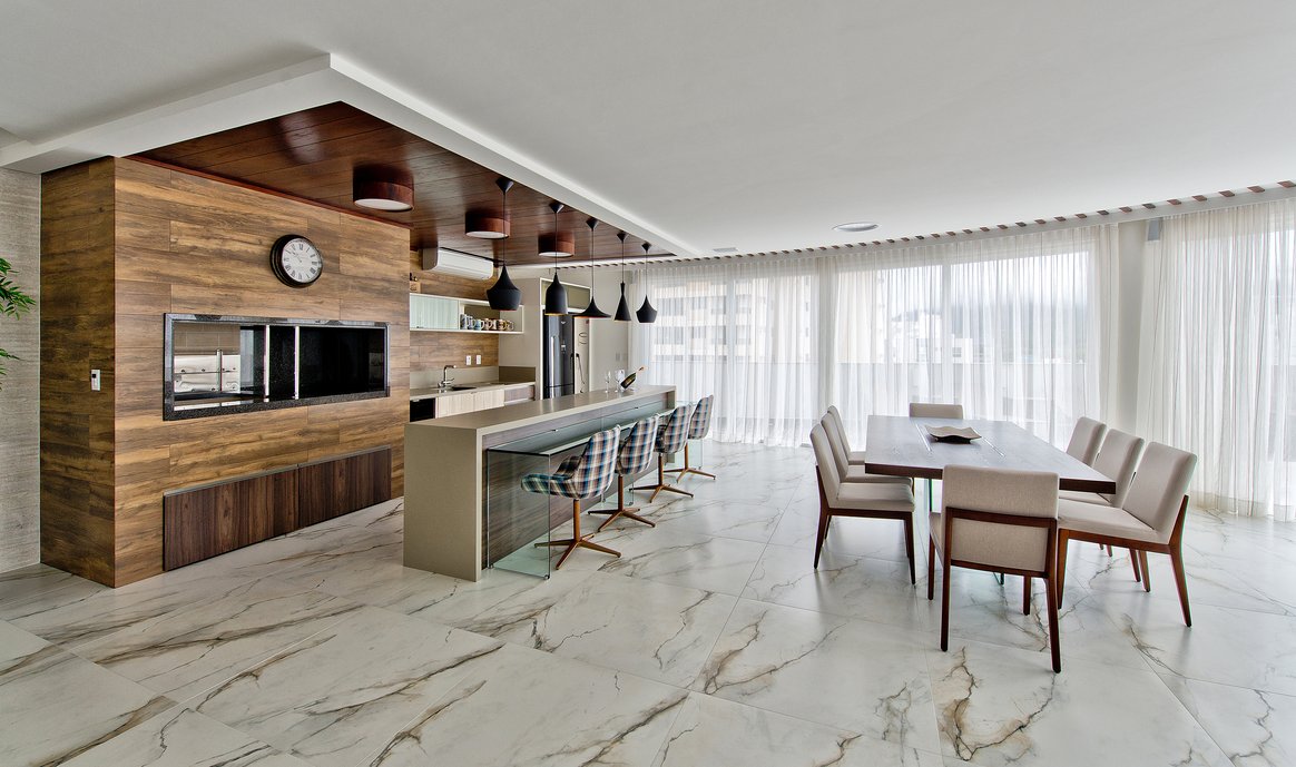 Espaço gourmet que acomoda até 25 pessoas para o proprietário receber bem os amigos e familiares. Porcelanato: Bianco Paonazzetto e Imbuia Clara.
