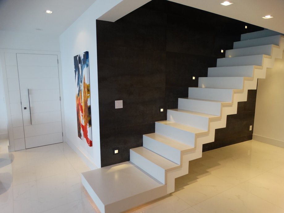 Escada revestida em Porcelanato branco com cortes especiais tendo como fundo porcelanato Denim e piso do living em Carrara polido