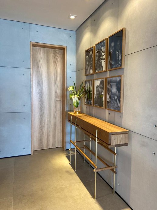 Hall de entrada com aparador do designer Gustavo Bittencourt e revestimento Tresuno nas paredes.