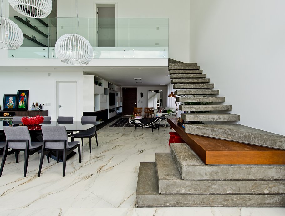 Espaço gourmet integrado ao living, com escada de concreto e madeira itaúba. Porcelanato: Bianco Paonazzetto.