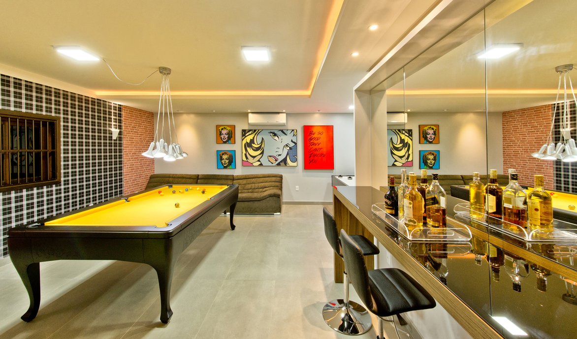 Sala de jogos com cores vibrantes. O pendente acima da mesa oferece uma iluminação direcionada, ideal para destacar a mesa. Porcelanato: Pietra di Firenze Argento.