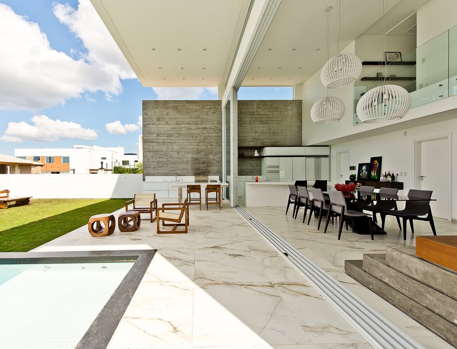 Integração das áreas interna e externa por meio do porcelanato Bianco Paonazzetto e das amplas aberturas.