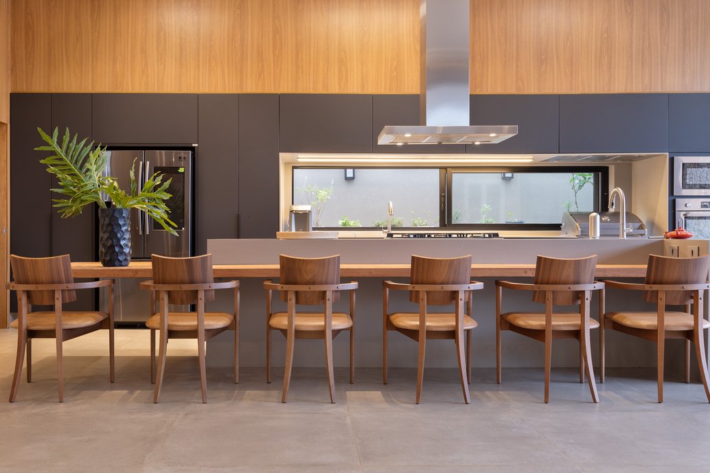 Cozinha gourmet com mesa em madeira natural e balcão em Corian em composição com o piso em cor concreto 