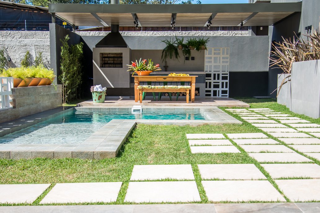 Esse espaço foi pensado para receber. Receber amigos. E a grande diferença está nos detalhes. Quase tudo é revestido com material cerâmico: o piso, as paredes, as floreiras, a piscina, a churrasqueira e o forro. A estrutura de cobertura é metálica e protege a área da pia e churrasqueira. Cobogós delimitam os espaços de parede, juntamente com a vegetação. Um pequeno estar, em outra extremidade, completa o ambiente de área externa.