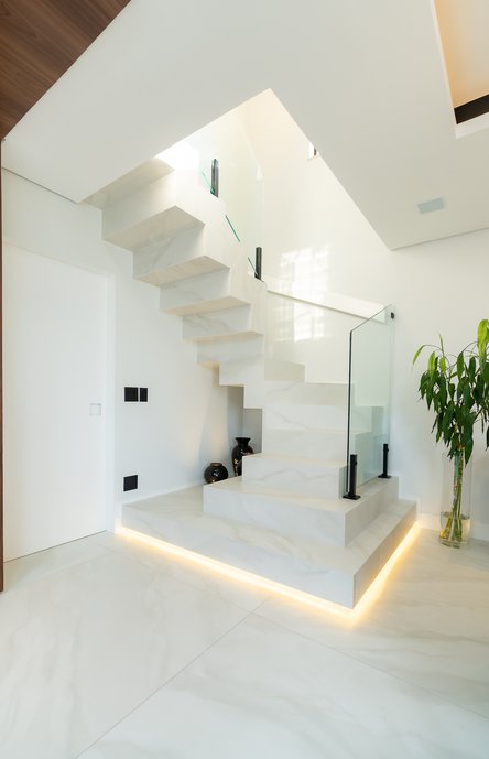 Escada revestida em Bianco Covelano, assentada em meia esquadria para o acabamento perfeito.