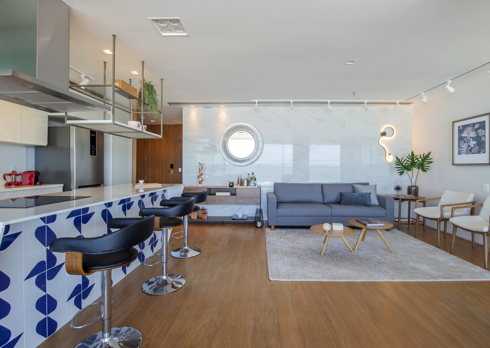 Living com cozinha aberta e painel em çporcelanato que como o polimento, reflete o mar em frente