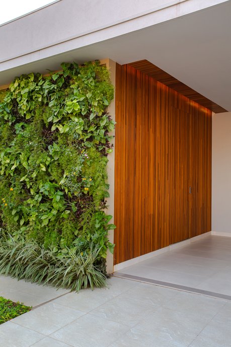 A fachada tem como destaque o painel brise de madeira natural e o jardim vertical. A composição dos pisos é neutra, juntamente com a cor da pintura externa, justamente para exaltar o painel e o jardim