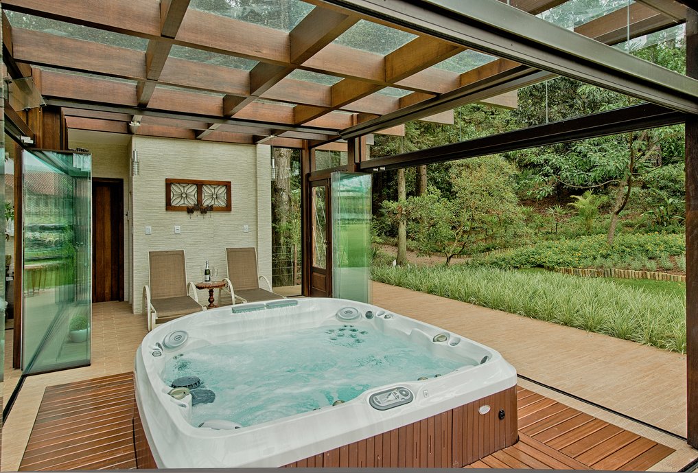 SPA na área externa de uma casa em Rio do Sul (SC), com jacuzzi e sauna. Porcelanato: Pietra di Savoia e Deck Peroba Envelhecida Castanho.