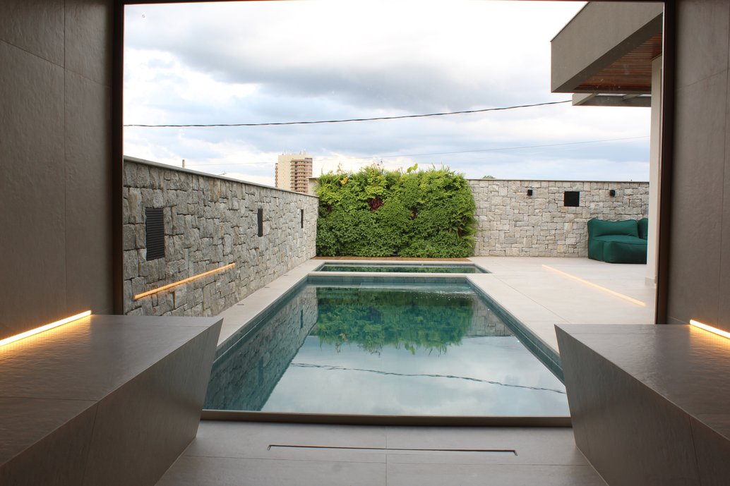 Sauna Dansk Cement Mud, area externa com piso porcelanato Posto 10 EXT formato 120x120cm e piscina na linha sunset.