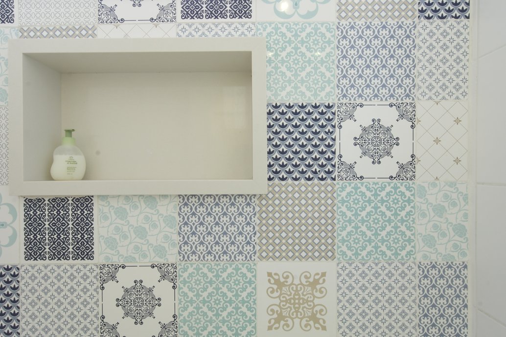 Dentro do box, montamos em uma das paredes um painel com o mais de azulejos Provence, com predominância do azul. O nicho foi feito em branco prime.