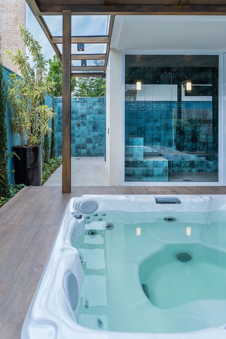Mais uma vez, pesar na integração é uma principal neste espaço, onde o platô da jacuzzi, da vista não só para o paisagismo à esquerda, mas também se integra à sauna de vidro criada. Os revestimentos migram de dentro para fora, criando espaços e ainda se une à parede com a cor exata presente nele. 