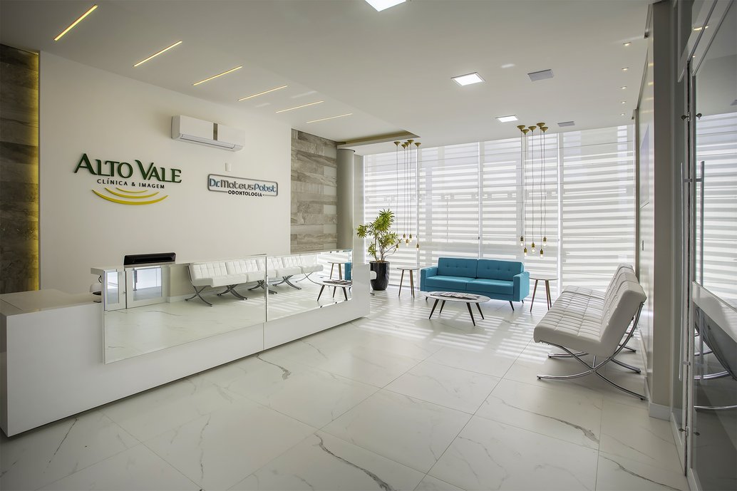 Recepção de edifício comercial em tons neutros e revestimentos na parede marmorizados que dão um toque especial aos pacientes e doutores que ali transitam.