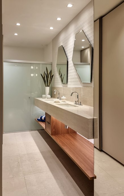 Banheiro de casal com destaque para painel porcelanato da bancada, valorizando os espelhos geometricos