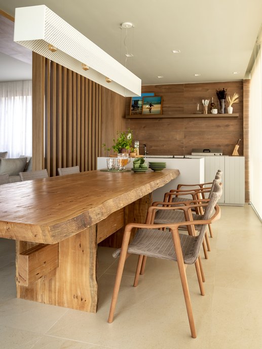 Varanda gourmet com mesa de tora de madeira desenhada pelo arquiteto