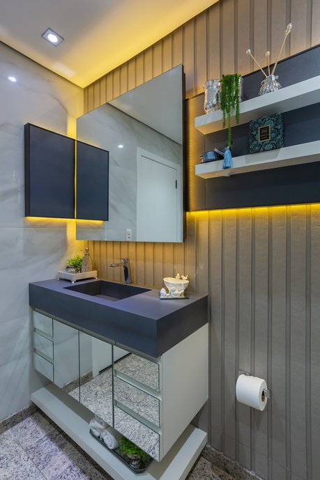 Banheiro social composto pela combinação de três diferentes revestimentos Portobello: Steel Blue na bancada da pia, no painel atrás do espelho e no nicho do box e Bianco Covelano nas demais paredes do banheiro.