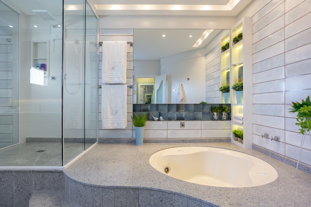Banheiro suíte composto pela combinação de dois diferentes revestimentos Portobello: Toki Chuva no nicho da banheira e Vitra Bianco como detalhe nas demais paredes do banheiro.
