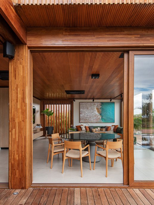 O deck flui, integrando o interno ao externo, por conta das esquadrias de vidro, permitindo a vista ampla do espaço.
