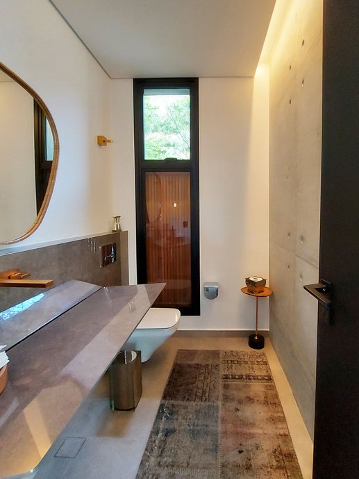 Lavabo com Bancada Ícaro, executada pela oficina Portobello. A meia parede, atrás da bancada, também foi feita no mesmo porcelanato da bancada, o Paloma Gris polido.