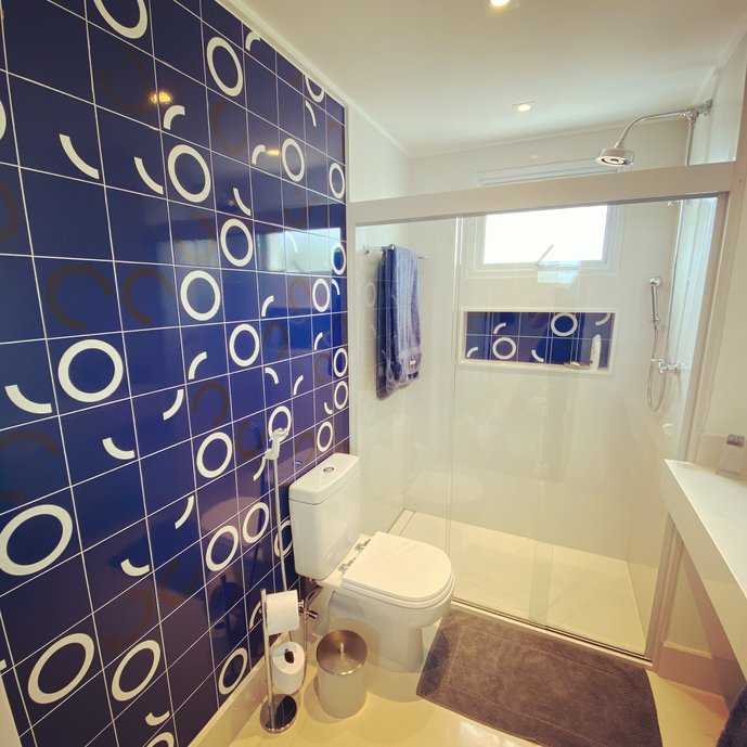 Banheiro casal com painel em tom de azul da coleção Athos Bulcão