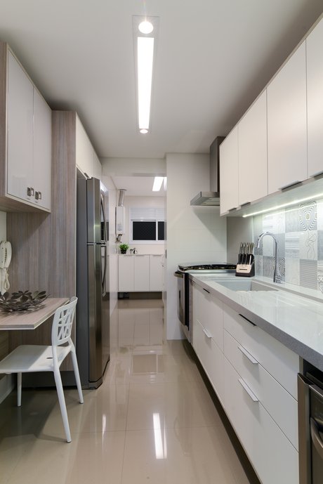 Cozinha com personalidade arrojada tem a cuba esculpida na bancada em Silestone, piso em porcelanato Mineral Argento e revestimento Vila Mada sobre a pia.