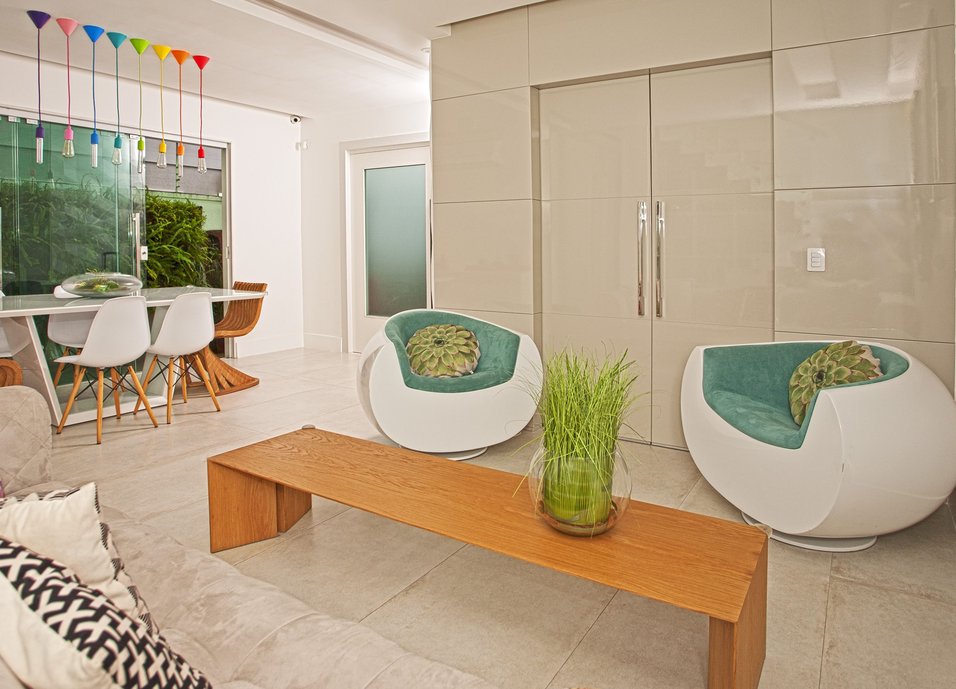 Sala com base cinza e branca - piso Concretyssima Match Off White, laca cinza no painel que abriga o acesso ao home theater. Toques em madeira para aquecer o ambiente