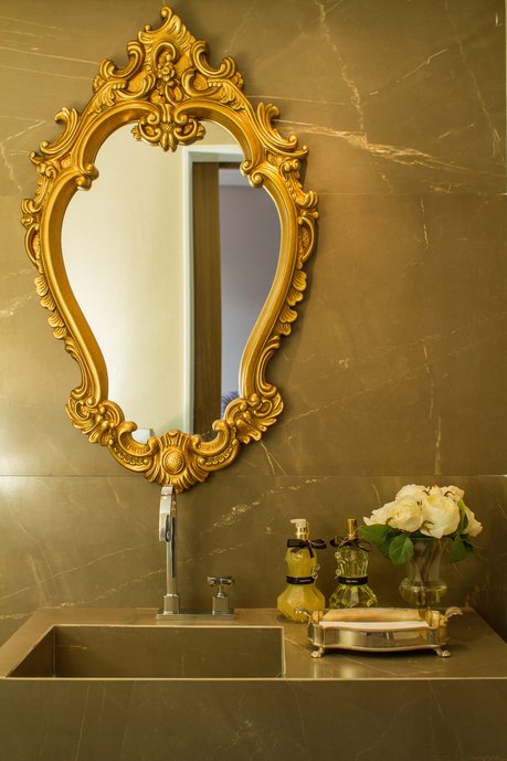 O porcelanato Bronze Armani usado na parede e lavatório dá uniformidade ao espaço pequeno do lavabo