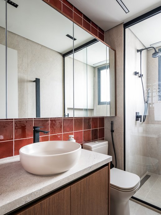 Lavabo com azulejo terracota brilhante, marcenaria em madeira e cuba de apoio. Contraste marcante e personalidade em cada detalhe.
