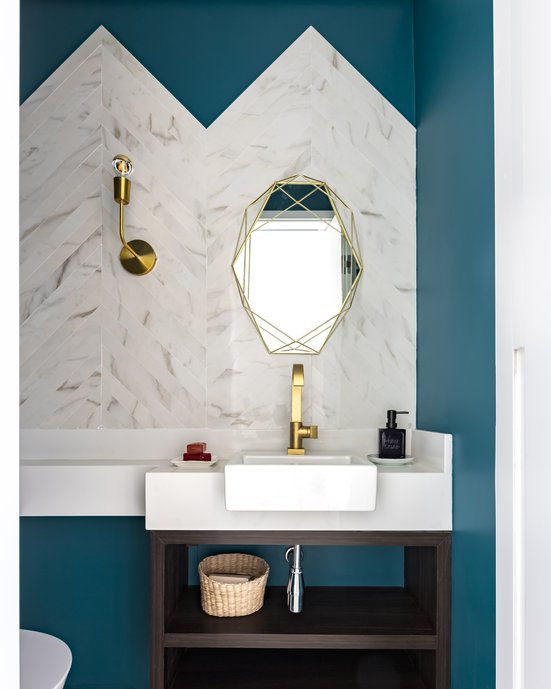 Lavabo com frontão em Chevron Golden Calacata, paredes em verde intesno e detalhes dos metais em dourado .