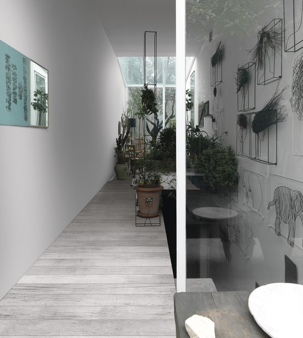 Corredor da escada com quadros e plantas. Piso com porcelanato - madeira branco e cinza.