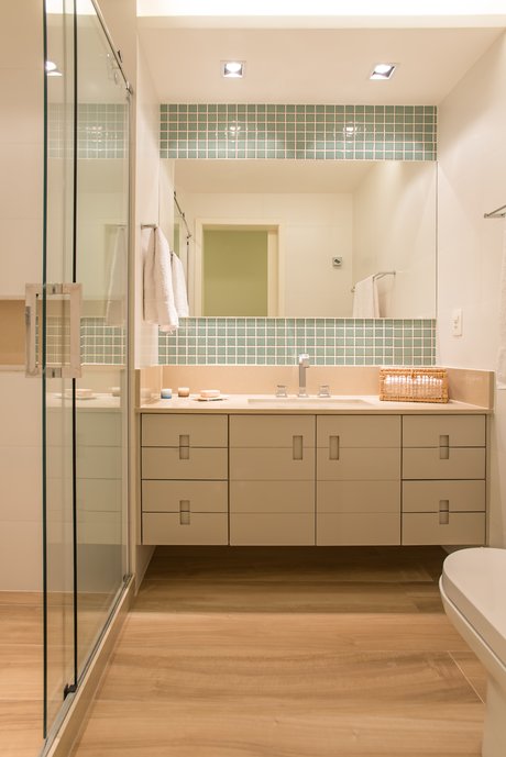 Banheiro para uso infantil, com uso de cores suaves nos revestimentos e marcenaria.Foram usadas pastilhas Glam Caribe, Porcelanato Araucária Clara e Cetim Bianco