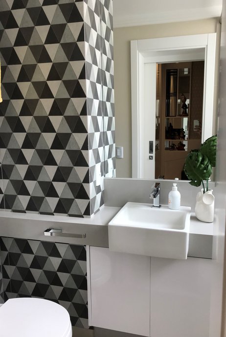 Lavabo com móveis claros em contraste com o revestimento de estampa geométrica em tons de preto, branco e cinza. (Ampla Design - Portobello: https://www.portobello.com.br/produtos/ampla-design/porcelanato/mini/60x60-natural/23105