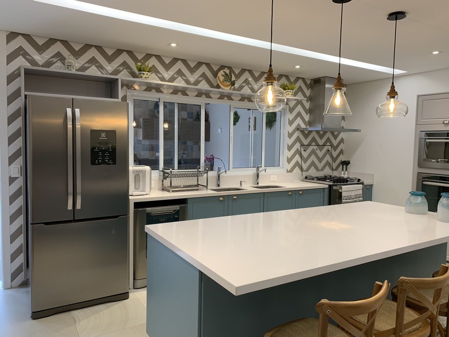 Cozinha estilo americana com ilha toda azil e branca, os revestimentos deram um charme a mais