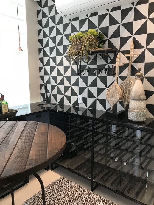 Móvel adega em metal preto para garrafas e parede principal com revestimento preto e branco.