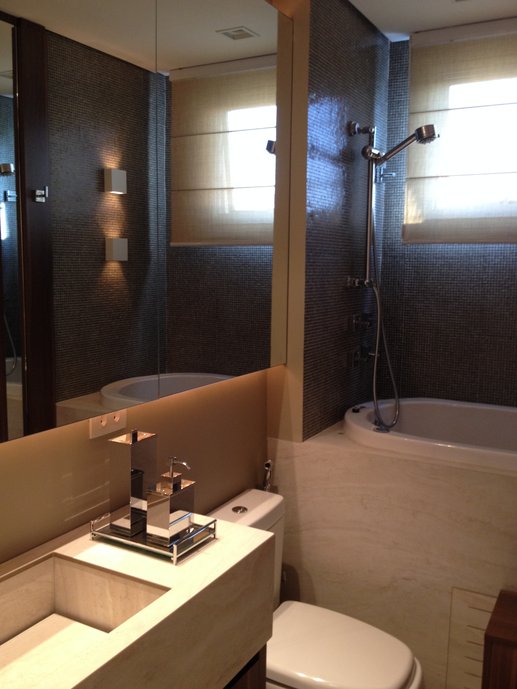 Banheiro com piso, volume banheira e bancada com cuba esculpida em Travertino BIANCO 60x120 NAT RET + detalhe parede banheira em Artesanal PETIT CONCRETO TEL 1x1