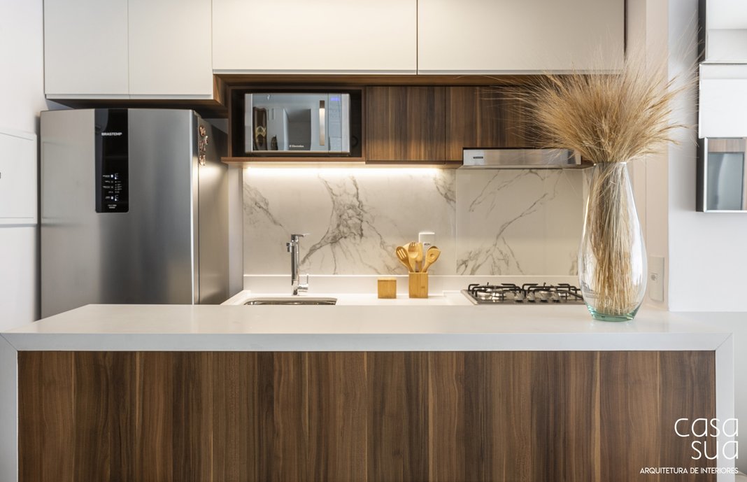 O porcelanato tipo mármore dá personalidade à cozinha. O porcelanato tipo madeira no piso aquece o ambiente predominantemente branco.