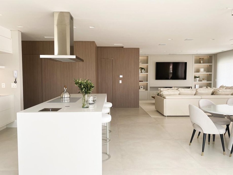 sala e cozinha integradas, com grande painel de madeira que abraça o hall de entrada e oculta as portas dos demais ambientes