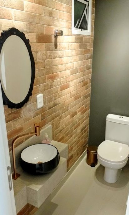 Vista geral do Lavabo do apartamento. Foram utilizados revestimentos Portobello na parede destaque do ambiente e na bancada. Para complementar, foram utilizados nos detalhes as cores preta e Rose Gold para combinar com as cores dos revestimentos e trazer para esse ambiente a ideia do rústico presente no restante do apartamento.