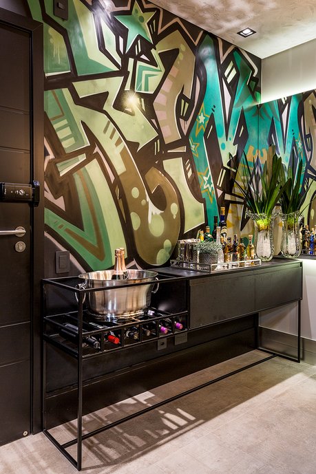 Apartamento jovem e descontraído em tons escuros; grafite em parede