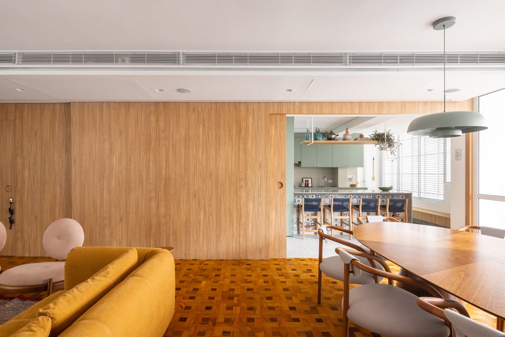 Integração da sala de estar com cozinha através de um painel ripado.