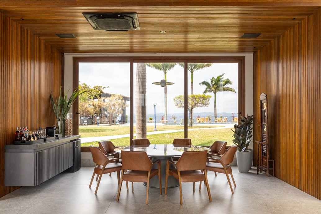 Sala de jantar com vista para o campo; madeira na parede e teto da sala