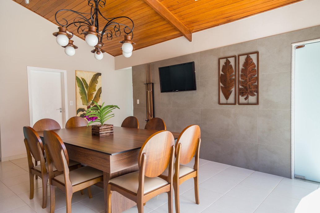 Essa mesa de refeições, deslizado o tampo, se transforma numa mesa de sinuca, onde a diversão se completa. O efeito natural do porcelanato Cement da linha Bauhaus da Portobello, aplicado na parede da varanda, deixa o ambiente aconchegante e em sintonia com o ambiente externo.