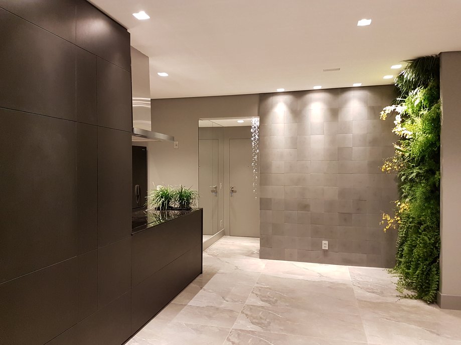 Sala de estar, com bancada de cooktop em granito e mdf pretos. O piso Noir St Laurent 60 x 1.20 foi usado em todo o apartamento. A cliente adora plantas então fizemos jardins verticais na sala e na varanda. E na bancada também foi previsto um local para plantas ou uma hortinha de temperos.
