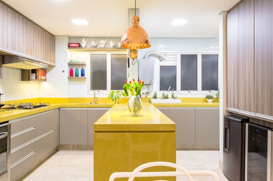 Uma cozinha toda aberta em tons de concreto onde o amarelo da bancada em padra sobressai